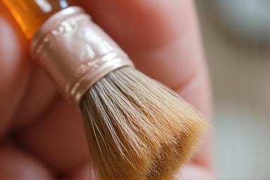 Soft brush gently dusting a delicate preserved floral arrangement, demonstrating careful cleaning techniques